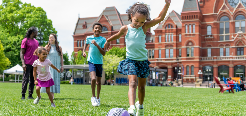 A family walks and has funny in the field at Washington Park in Over-the-Rhine.